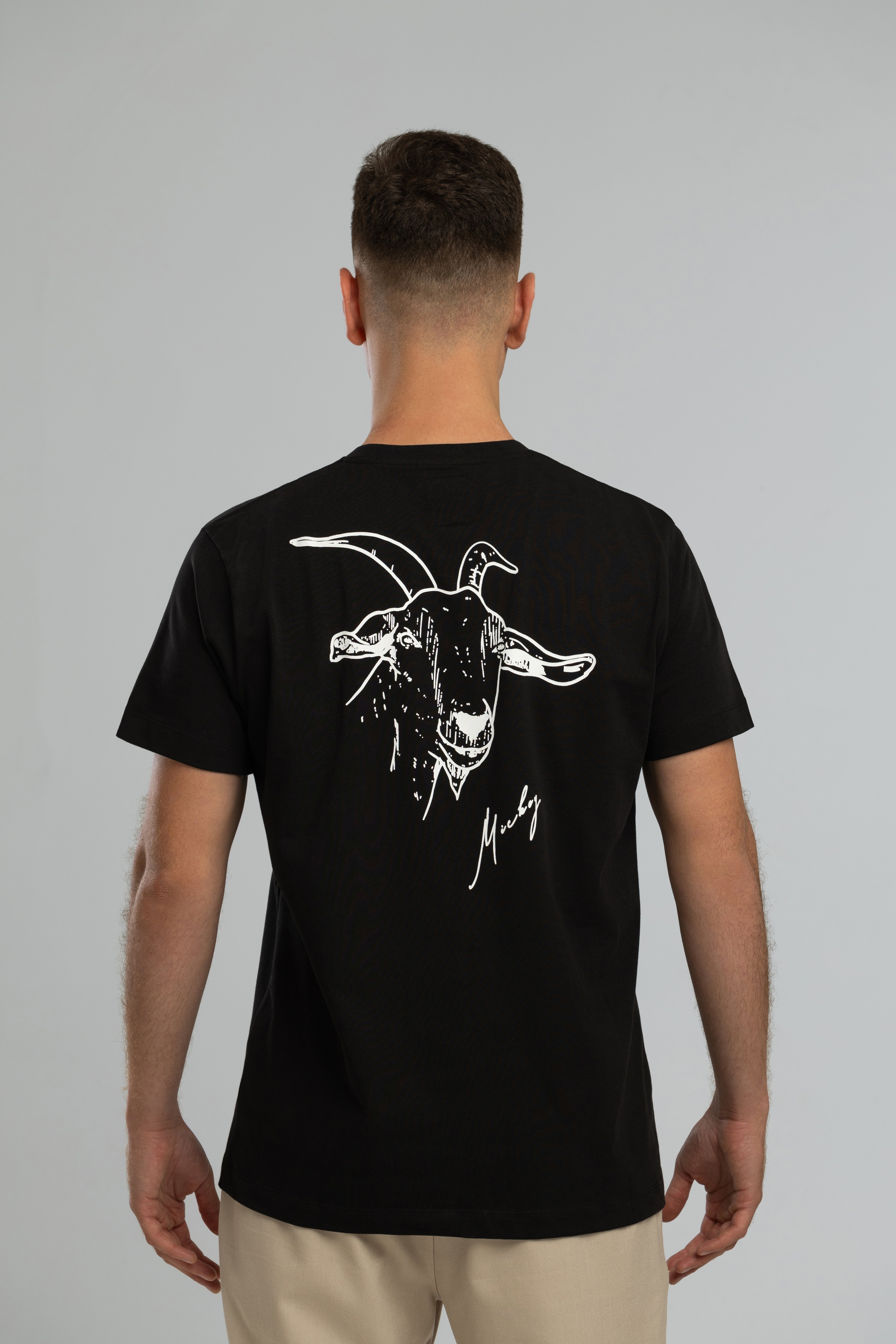 Schwarzes T-Shirt im Stil von Mickey the Goat mit seitlichem Wilderness Cooking-Logo